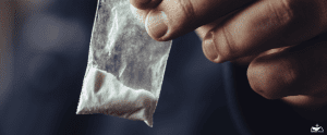HHRC-Man hand holds plastic packet or bag with cocaine or another drugs, drug abuse and danger addiction concept